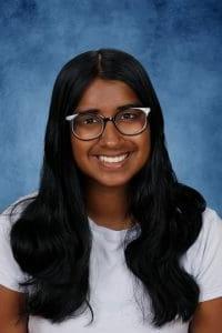 Smiling young woman with glasses on blue background.